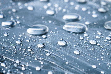 Close-up of raindrops of different sizes on the surface covered with cling film. Moisture weather and humidity concept