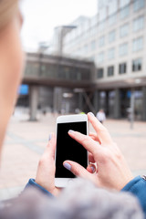 Businesswoman uses a mobile phone on the street against an office building.