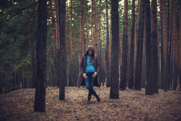 Pretty happy woman posing in forest and looking at camera.