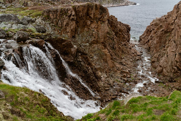 Stormy waters of the northern waterfall in a rocky gorge on the shores of the cold sea
