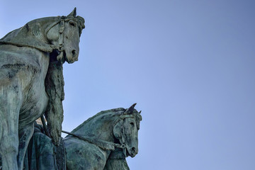 Fototapeta na wymiar Fragment of the Millennium Monument on the Heroes' Square in Budapest, Hungary. Side view on statue horses of the chieftains of the Magyars against a blue sky. Close-up. Selective focus. Copy space.