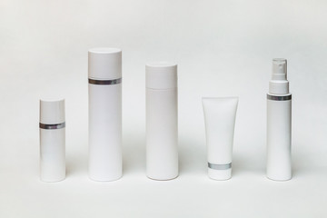 five different white bottles and tubes for cosmetics on a white background