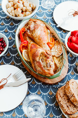 Festive dish for Thanksgiving, roasted turkey legs with vegetables on a table with snacks.