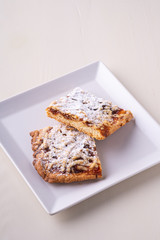 Two pieces of homemade cookies apricot jam powdered sugar in white square plate