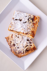 Two pieces of homemade cookies apricot jam powdered sugar in white square plate