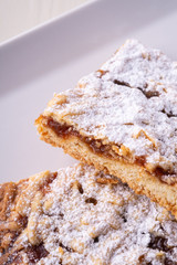 Two pieces of homemade cookies apricot jam powdered sugar in white square plate