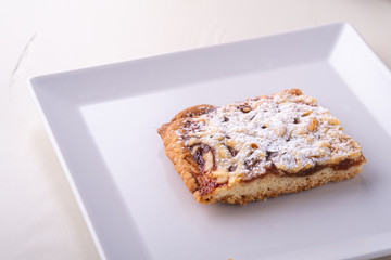One single pieces of homemade cookies apricot jam powdered sugar in white square plate