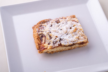 One single pieces of homemade cookies apricot jam powdered sugar in white square plate