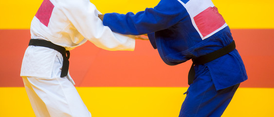 Two judo fighters in white and blue uniform.
