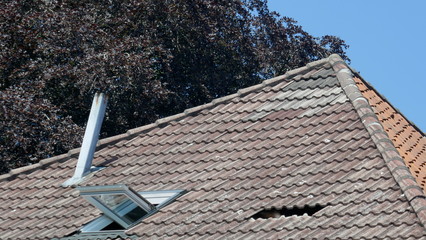 Hole in the roof of a house. Roof damage. Broken tile roof after a storm.