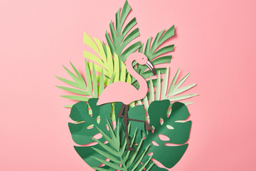 top view of paper cut flamingos on green palm leaves on pink background