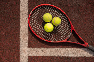 Top view of three tennis balls on racket on sports playground