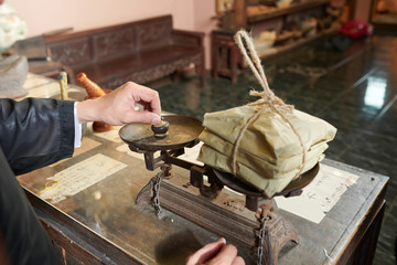 Chinese medicine practitioner using traditional old scales to weight paper packages