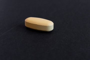 yellol pill, tablet isolated on dark / grey background