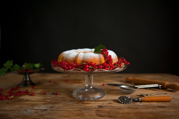 Bundt cake with currant and roses flowers on the black background.