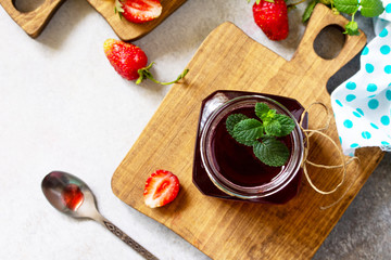 Homemade preservation. Fresh strawberry berries and strawberry berry syrup on a light stone table. Top view flat lay background.