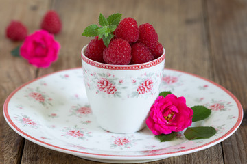 Tischdekoration mit Himbeeren im Becher und Rosen