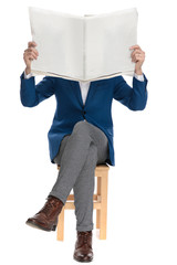 Casual man holding a newspaper over his face