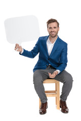 Positive casual guy holding a blank speech bubble