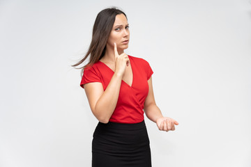 Portrait to the waist of a young pretty brunette woman of 30 years old in a bright red sweater with beautiful dark hair. Standing on a white background, talking, showing hands, with emotions