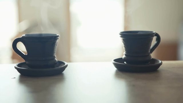 Waiter bringing a fresh maiden coffee in black clay cup and putting on table close up view. Coffee consummation in modern coffee shop concept cinematic Slow motion footage.
