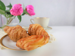 breakfast with cup of coffee and croissants, bouquet of pink flowers