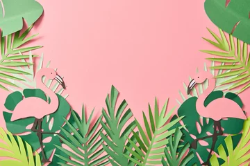  top view of paper cut flamingos on green palm leaves on pink background with copy space © LIGHTFIELD STUDIOS