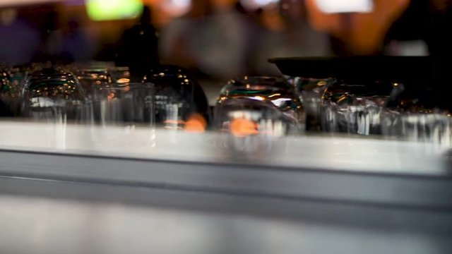 Looking in through a bar window with lines of drink glasses ready to be used.