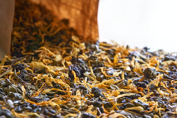 Herbal tea closeup. Multi coloured dried herbal tea leaves and brown kraft paper bag with selective focus.