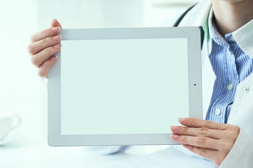 Mid section of female medicine doctor shows tablet computer with white screen. Contact information exchange, introducing gesture at formal meeting concept