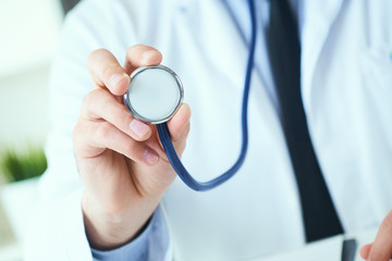 Close-up of a doctor's hand holding a stethoscope outstretched towards the viewer. Medic shop or store, physical and disease prevention, er consultant, 911, pulse measure, healthy lifestyle concept