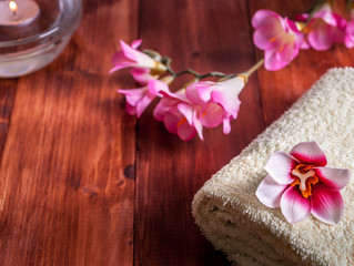 Fototapeta na wymiar Towel with flowers and a candle on a wooden background