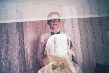 The groom holds the mirror. display in the window. Happy groom pose. wedding morning. background. Smile, portrait. The groom glasses. close up.