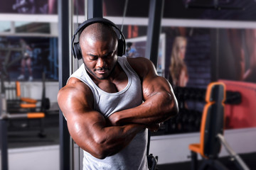 The athlete listens to music on headphones from his smartphone in the gym
