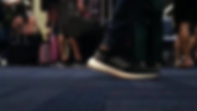 The detailed view of legs walks on carpet in hall, slow motion. A blurred passengers on to the airport, close up.