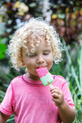  little boy with blonde curly hair is eating ice cream