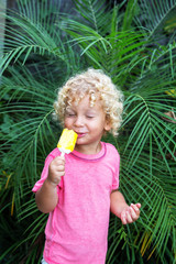  little boy with blonde curly hair is eating ice cream