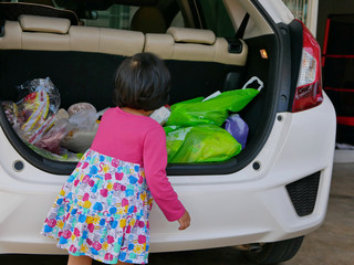 Little baby girl help carrying stuff from the back of the car into the house, after coming back...