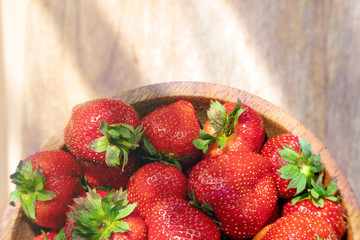 Fresh beautiful strawberries in wooden bowl top view. Strawberry fruits on wooden table copy space.