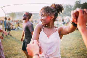 African American young woman with friends dancing at summer holi festival
