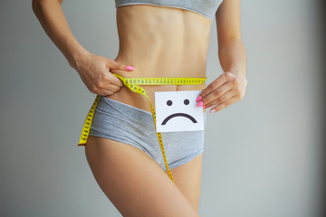 Hands measuring waist with a tape. Slim and healthy woman at her home