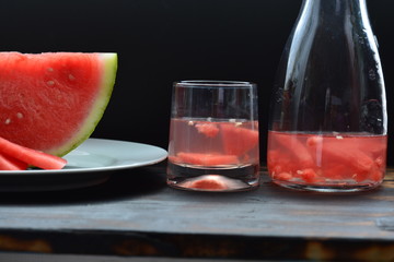 red water melon juice in a glass and jug at summer on black background