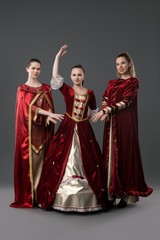 Three girls in gorgeous queen red dresses view