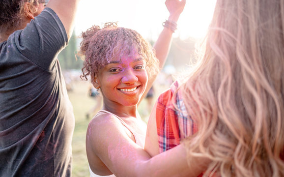 African American young woman covered in colorful powder with friends at holi festival