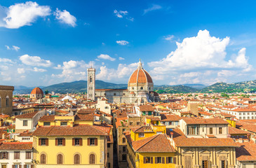 Fototapeta premium Top aerial panoramic view of Florence city with Duomo Cattedrale di Santa Maria del Fiore cathedral, buildings houses with orange red tiled roofs and hills range, blue sky white clouds, Tuscany, Italy