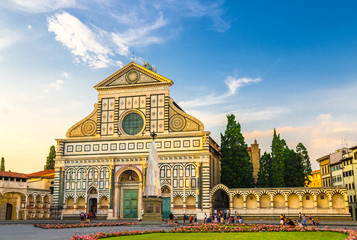 Basilica di Santa Maria Novella and green grass lawn with flowers on Piazza Santa Maria Novella square in historical centre of Florence city, blue sky white clouds, Tuscany, Italy - obrazy, fototapety, plakaty