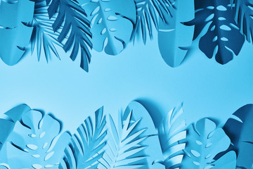 Fototapeta na wymiar top view of blue exotic paper cut palm leaves on blue background with copy space
