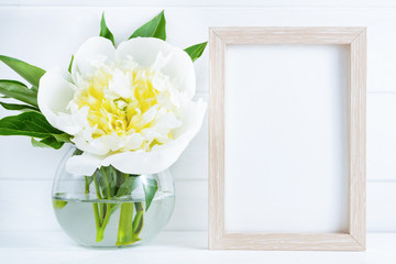White peony flower in vase on white wooden background with mockup or copy space.