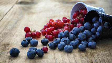 Combination of blueberries and cranberries rolled over on wooden table