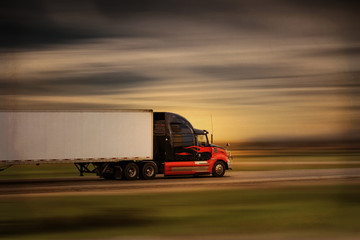 Bright modern big rig semi truck and trailer in motion on a highway